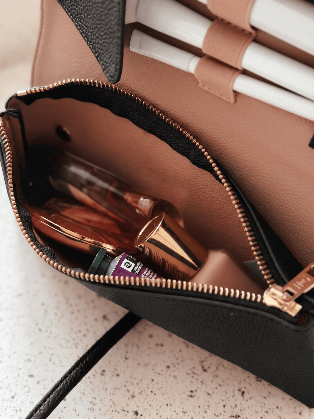 Marli Essentials Pouch in Charcoal styled with lipstick and a mirror on a speckled surface