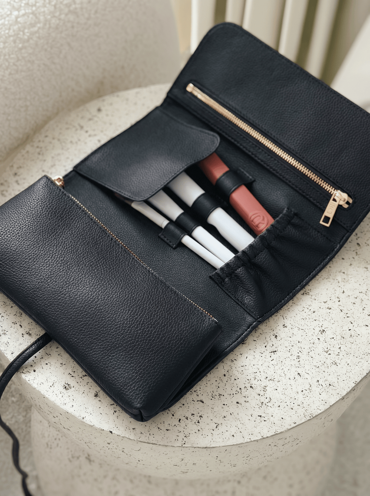 Marli Essentials Pouch in Charcoal styled with makeup brushes on a light surface